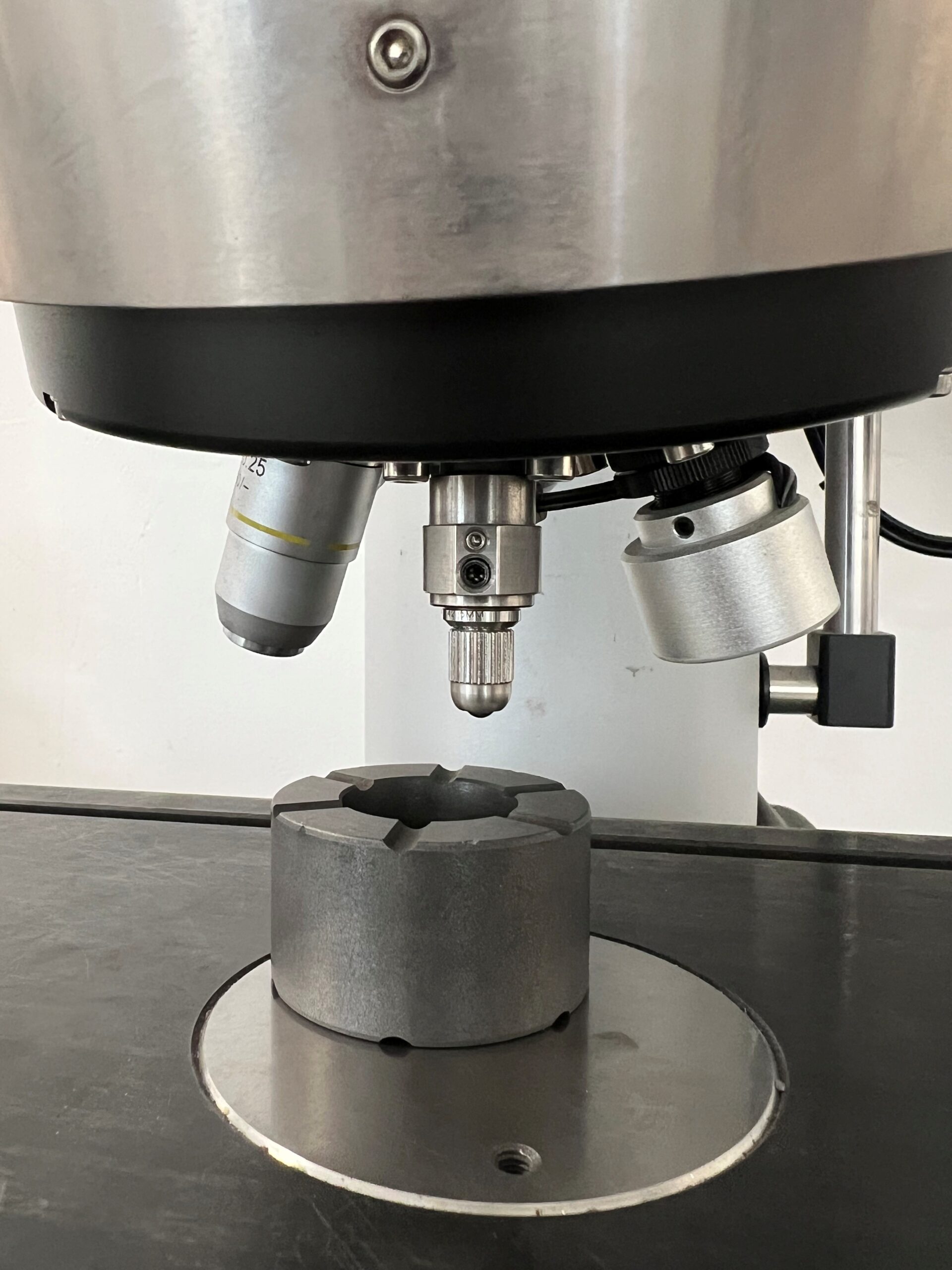 Hartmetallkugel als Eindringkörper über einer Kohlenstoffprobe: Aufbau für die Rockwell-Härteprüfung HR5/150 nach DIN 51917.